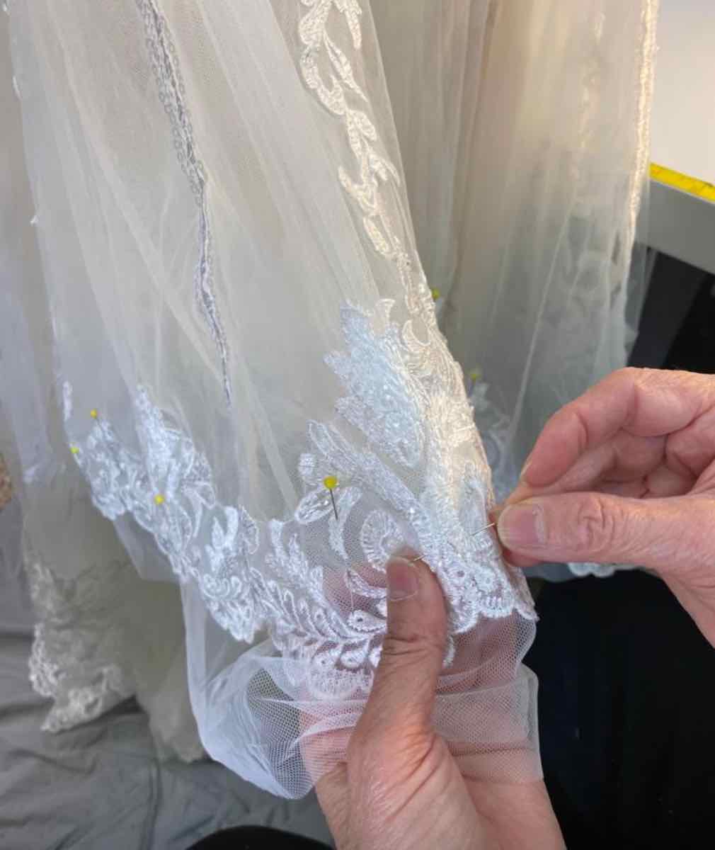 Hand-pinning lace on a bridal gown